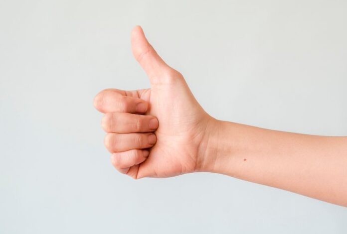 person s right hand doing thumbs up