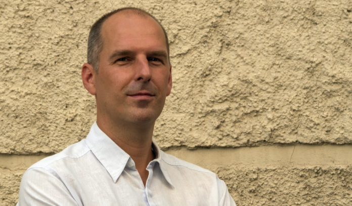 Alex Marini davanti a un muro in pietra