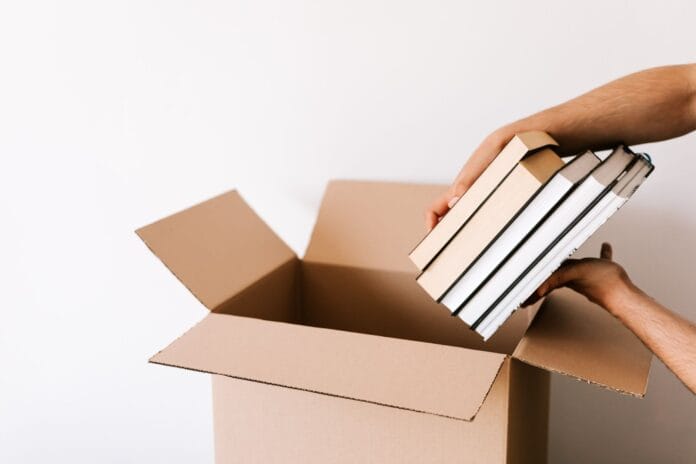 pexels-photo-4498140 crop man packing stack of books in opened cardboard box