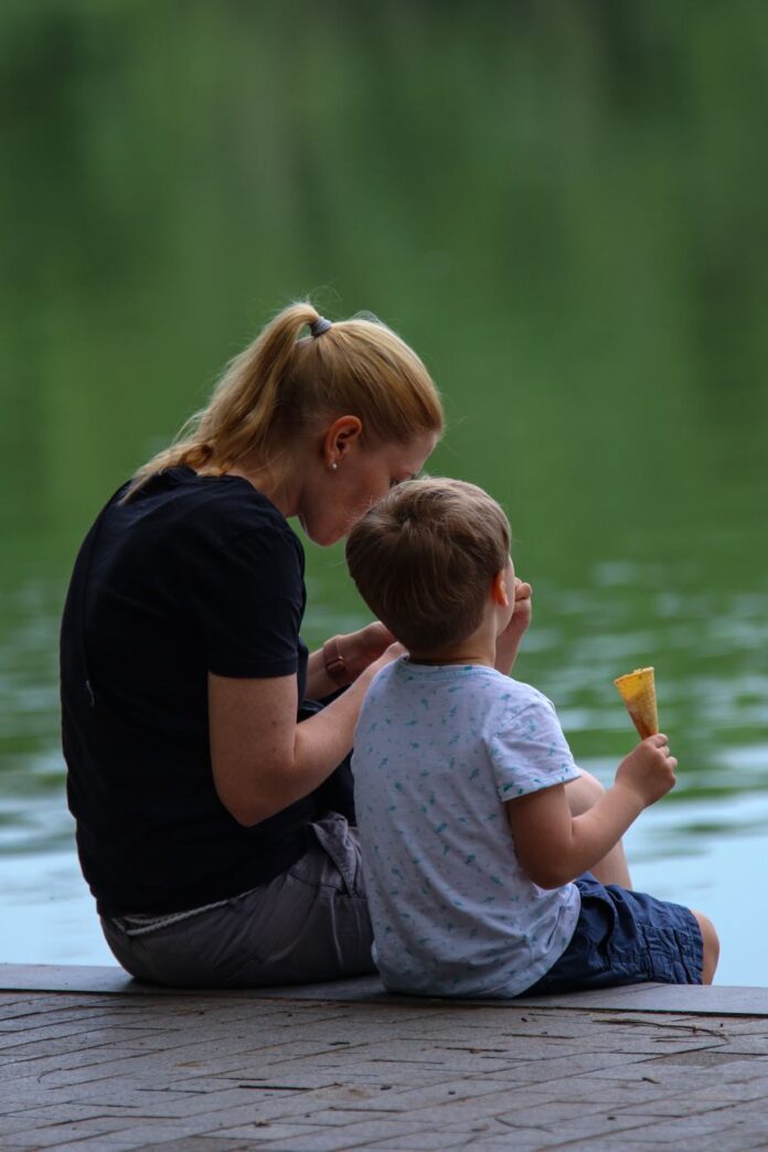 mother and child enjoying ice cream by the lake