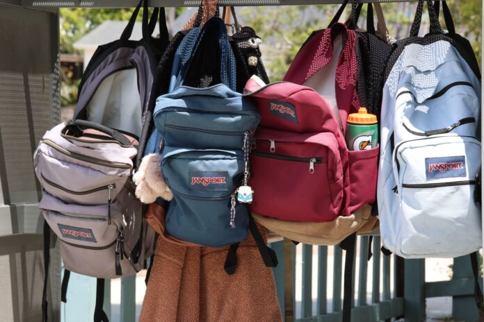 Zaini scolastici colorati appesi all’aperto, pronti per il riuso